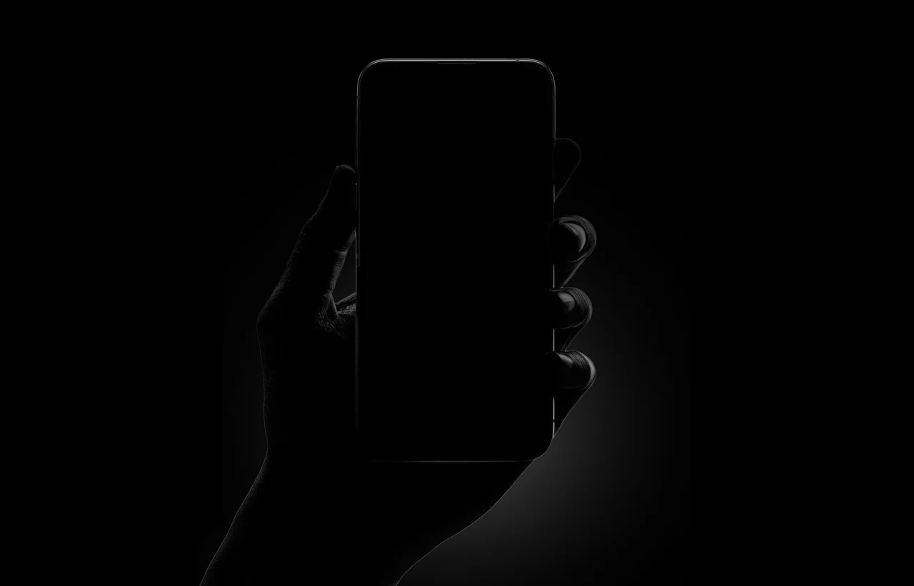 Eine Hand hält ein Smartphone, als Scherenschnitt vor schwarzem Grund