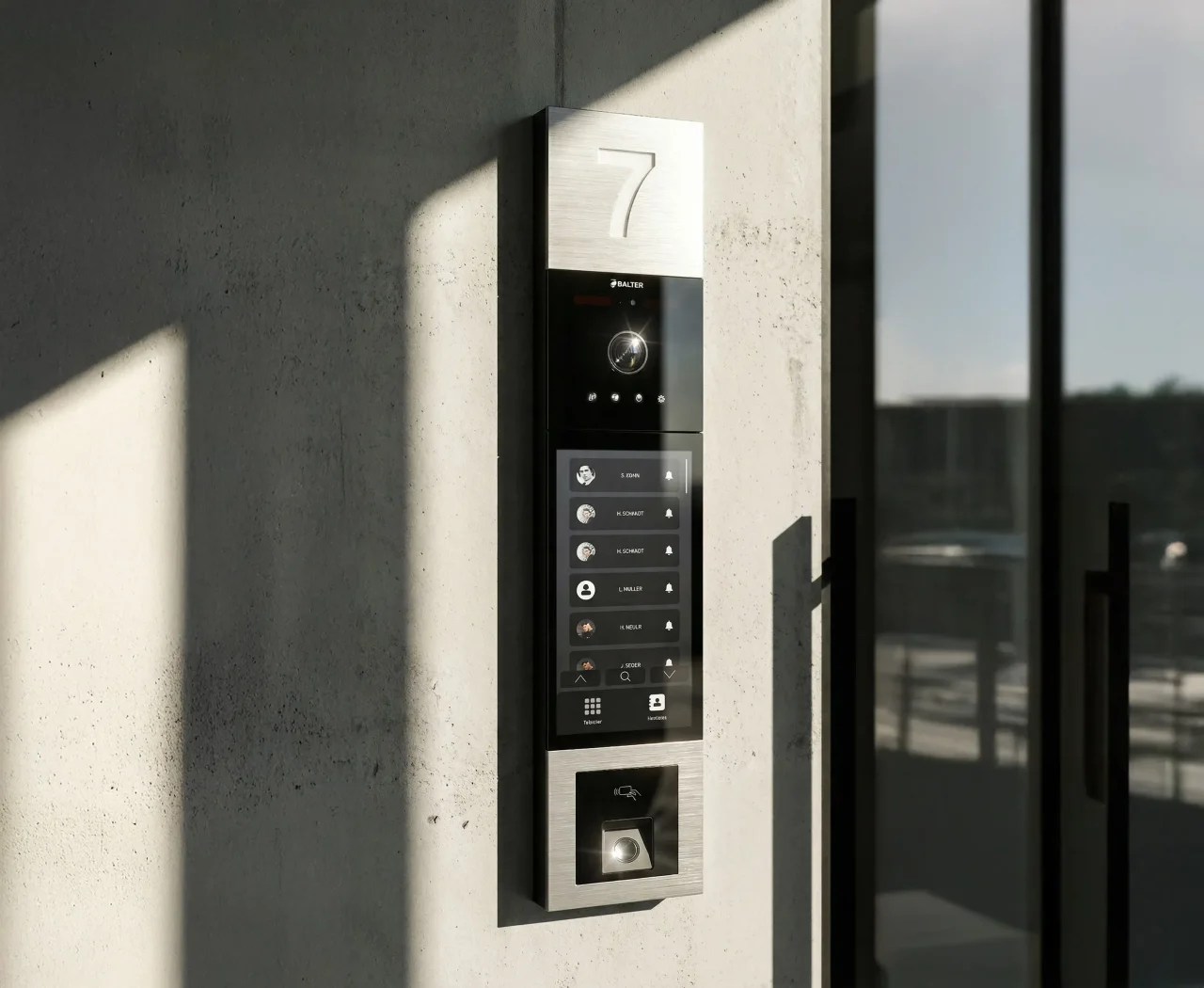Türstation mit Klingeltafel im Sonnenlicht an einer Betonfassade